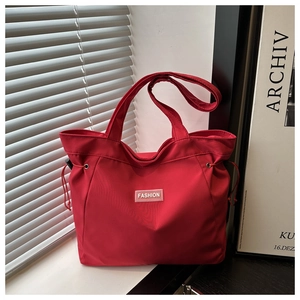 Detail of red canvas tote bag with fashion tag and drawstring design for daily use