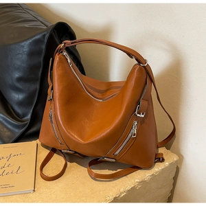 Detail of caramel brown leather tote bag with metallic zipper and adjustable straps
