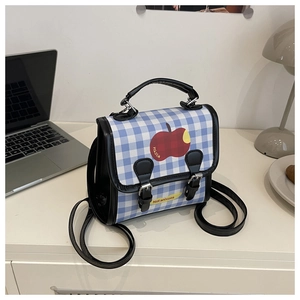 Detailed view of blue gingham backpack with red apple design and black leather straps