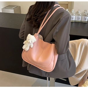 Pink faux leather tote bag with decorative stitching and a white plush bear charm