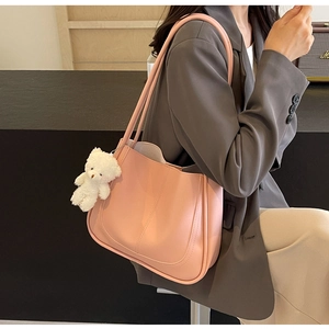 Detailed view of pink textured leather tote bag with a cute white plush bear charm
