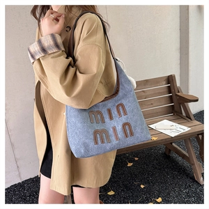 Detail of blue denim tote bag with min min embroidery and white plush keychain accessory