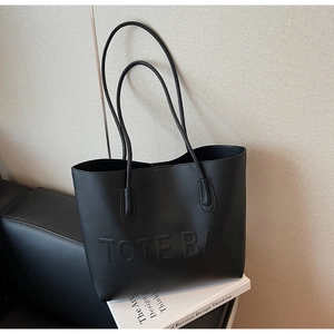 Détail du lettrage TOTE BAG embossé sur le cuir noir mat avec des fines poignées