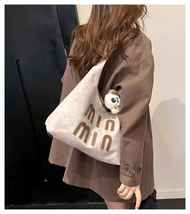 Detail of canvas hobo tote with leather letter embroidery and plush puppy pendant