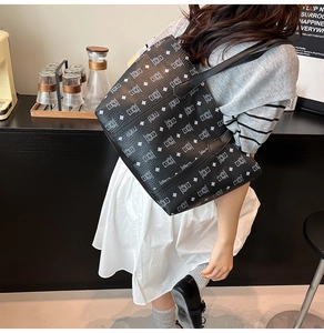 Detail view of large black leather tote bag with pattern and handmade label on handle