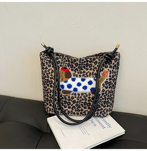 Détail du sac seau léopard avec broderie de chien de dessin animé sur un canapé noir