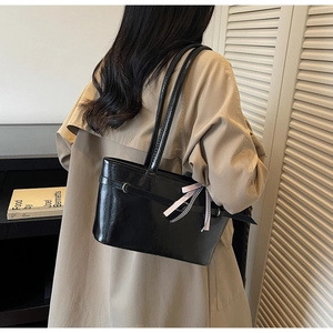Dettaglio della borsa tote in pelle verniciata nera lucida con nastri decorativi a spalla