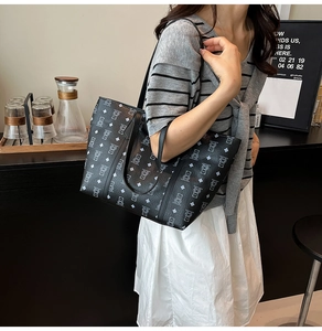 Detail of a black oversized tote bag with bear print pattern worn in a cafe setting