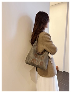 Side view of olive green oversized suede tote bag with letter patches shown on model