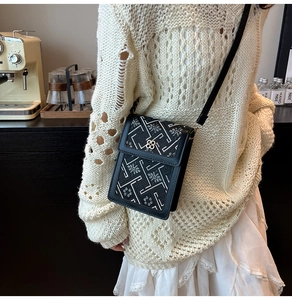 Detail of embroidered floral phone crossbody bag with clover buckle in a warm studio setting