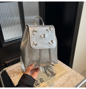 Detail of silver metallic backpack featuring five 3D metal butterfly buckles and drawstring