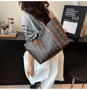 Retro monogram tote bag with brown leather handles worn by a model in a stylish setting