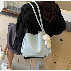 Detailed view of light blue tote bag with plush bear charm in a lifestyle setting