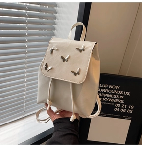 Detail of a creamy white PU leather mini backpack with five silver metal butterfly studs