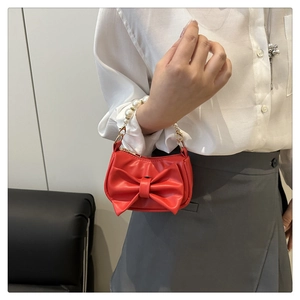 Close-up of red mini handbag featuring a large bow and a white pearl bead handle