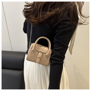 Detail of beige leather mini square bag with silver chain strap shown on a model