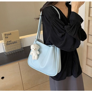 Light blue faux leather square shoulder bag with plush bear charm and decorative stitching