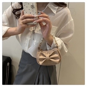 Detail of elegant beige leather handbag with large bow and luxurious pearl handle