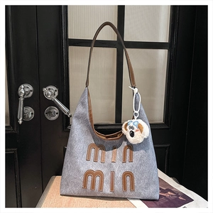 Detail of grey felt tote bag with leather letter patch and cute puppy plush charm