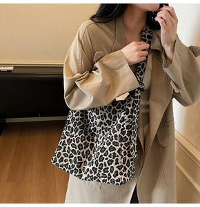 Detail of leopard print canvas tote bag with fashion label shown on a khaki trench coat