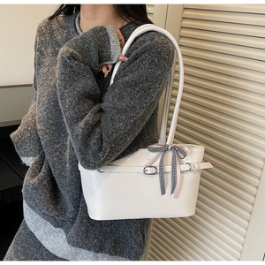 Zijaanzicht van de witte leren tote bag met een zwart-wit geruite strik op model