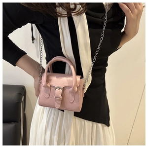 Pink mini crossbody bag with silver buckle worn by model showing style and scale