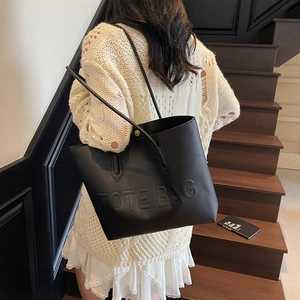 Sac fourre-tout noir minimaliste avec texte embossé et longues bandoulières