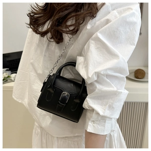 Detail of a black square leather handbag with silver metal buckle and chain strap
