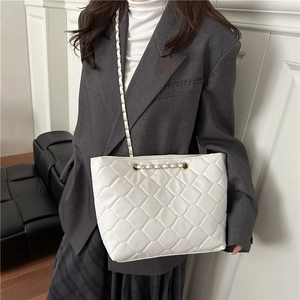 Sac cabas matelassé blanc cassé avec bandoulière chaîne porté sur un blazer gris chic