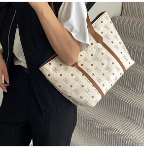 Detail of a large white tote bag with bear pattern and brown leather straps on shoulder