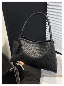 Dettaglio borsa nera intrecciata con manico annodato e mini pochette coordinata