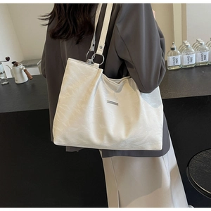 Detail of off-white tote bag showing crinkled texture and metal hardware accents