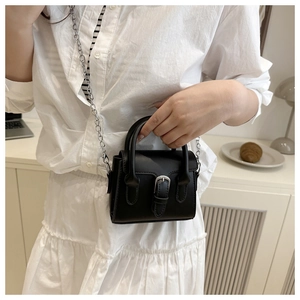 Detail of a mini black crossbody bag featuring a silver buckle and chain shoulder strap