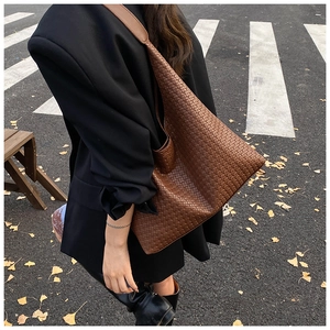 Dettaglio della texture intrecciata marrone di una grande borsa a tracolla minimalista