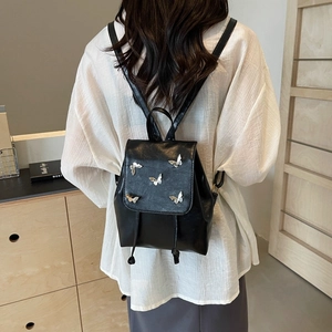 Minimalist black faux leather backpack featuring silver butterfly charms and drawstring flap