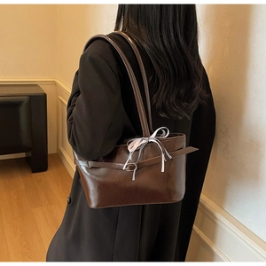 Dettaglio della borsa tote marrone scuro con cinturini in pelle e fiocco a quadretti