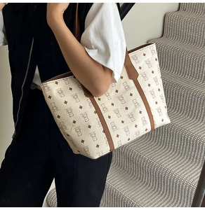 Detail of premium beige tote bag with brown bear pattern and leather texture handles