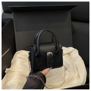Detail of a black mini leather square bag with silver buckle and metal chain strap