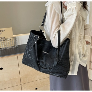 Detail of black tote bag featuring crinkled texture fabric and silver metal hardware