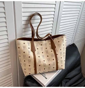 Close-up of a stylish tote bag featuring bear prints and brown leather handles