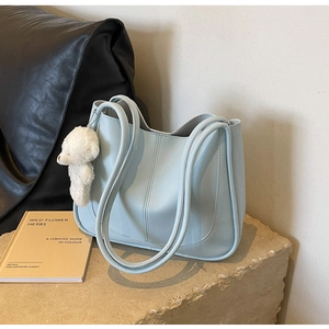 Detail of light blue PU leather tote bag with vertical stitching and white bear charm