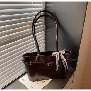 Dettaglio borsa tote marrone lucido con fibbia in metallo e fiocco a scacchi elegante