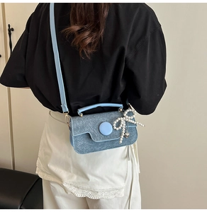Détail du petit sac carré en denim bleu clair avec nœud en perles et breloque cœur