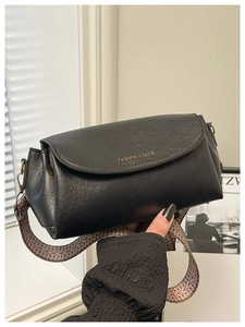 Détail du sac à main noir en cuir grainé avec une large bandoulière tissée à motif géométrique