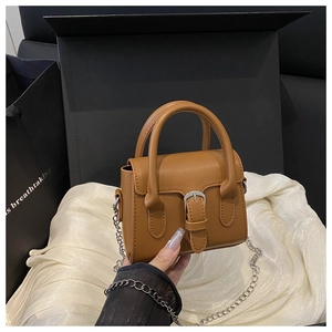 Close-up of caramel mini square bag with silver metal buckle and chain strap