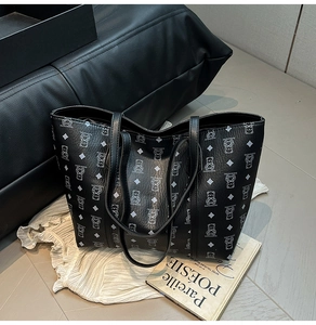Detail shot of black tote bag with cartoon bear pattern on white textured fabric