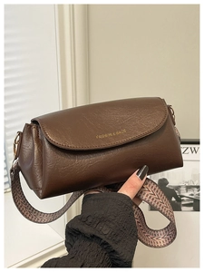 Détail du sac oreiller en cuir marron foncé avec large bandoulière tissée géométrique