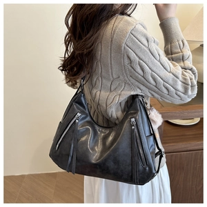 Side view of large black leather hobo bag with fringe zippers worn by a model