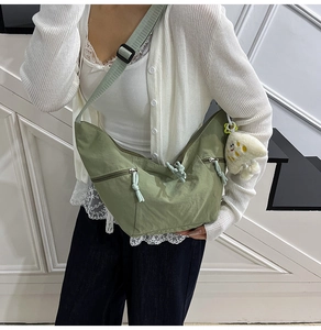 Detail of light green crescent nylon bag with adjustable strap and plush cloud pendant
