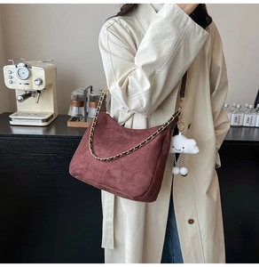 Détail du sac demi-lune en daim bordeaux avec chaîne dorée et breloque nuage